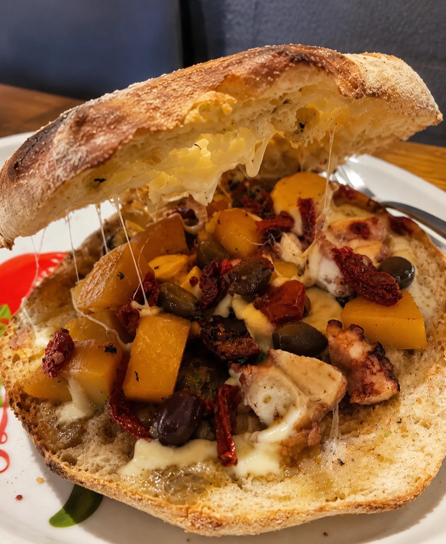 Puccia salentina aperta, farcita con polpo, patate gialle, olive, capperi, pomodori secchi e formaggio filante